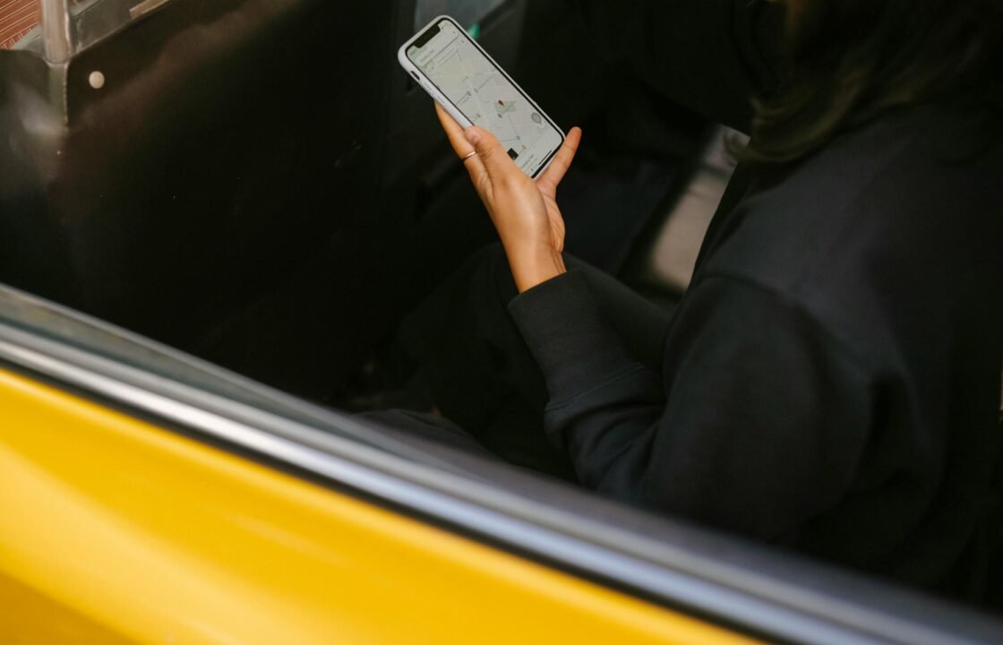 A woman using a smartphone for navigation in a yellow taxi. Perfect for travel and technology themes.