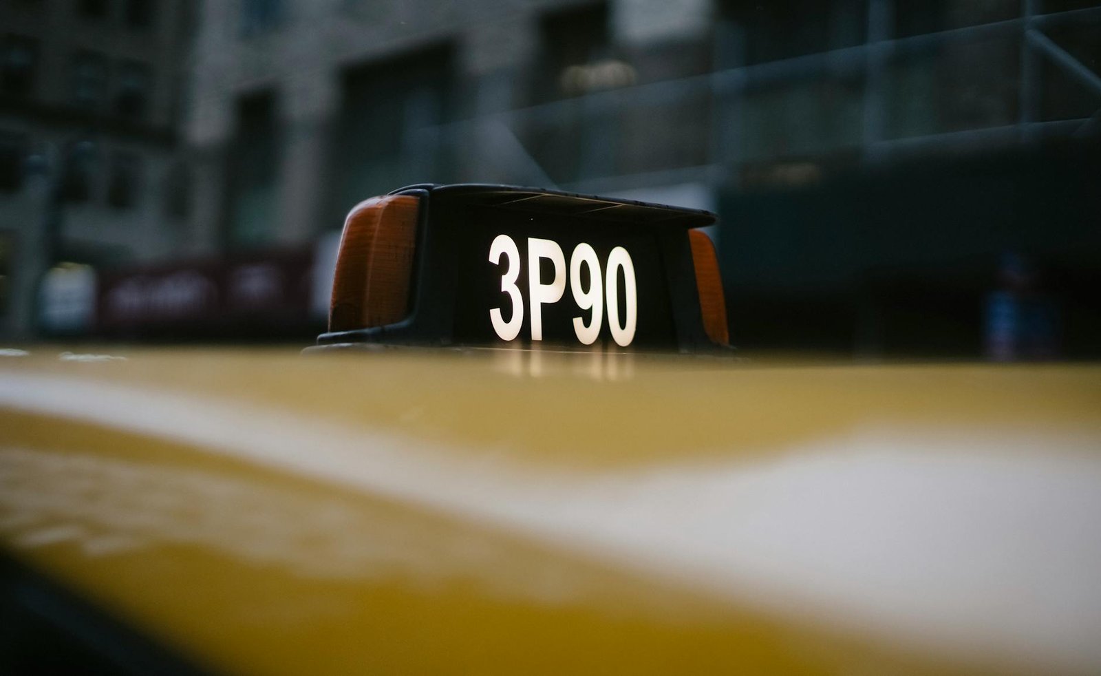 Close-up of a yellow taxi roof sign with 3P90 code in urban setting.